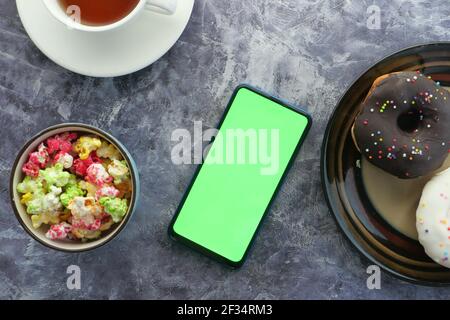 Draufsicht auf Smartphone und Popcorn auf dem Tisch Stockfoto