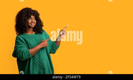 Attraktive schwarze Frau in gestricktem Pullover zeigt auf Kopie Raum Stockfoto