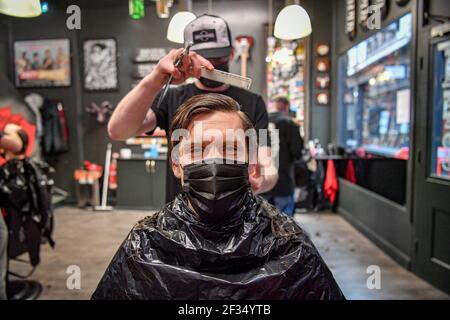 David Saunders, 38, aus Cardiff, sitzt im Barbers Chair im Sleep When You're Dead Barbers in Duke St Arcade, Cardiff, während er seinen ersten Haarschnitt seit Sommer 2020 hat. Friseure und Barbiere in Wales werden ab Montag zum ersten Mal im Jahr 2021 wiedereröffnet, da die Beschränkungen für Coronaviren gelockert werden, was die erste Aufhebung der Regeln für Dienstleistungen mit engen Kontakten seit der Sperre von Wales am 20. Dezember markiert. Geschäfte wie Nagelstudios und Schönheitssalons werden voraussichtlich bis mindestens April 12 geschlossen bleiben. Bilddatum: Montag, 15. März 2021. Stockfoto