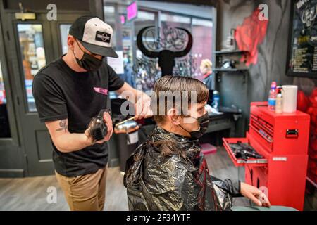 Barber Olly D'Urso schneidet David Saunders, 38, aus Cardiff, bei Sleep When You're Dead Barbers in Duke St Arcade, Cardiff, da David seinen ersten Haarschnitt seit Sommer 2020 hat. Friseure und Barbiere in Wales werden ab Montag zum ersten Mal im Jahr 2021 wiedereröffnet, da die Beschränkungen für Coronaviren gelockert werden, was die erste Aufhebung der Regeln für Dienstleistungen mit engen Kontakten seit der Sperre von Wales am 20. Dezember markiert. Geschäfte wie Nagelstudios und Schönheitssalons werden voraussichtlich bis mindestens April 12 geschlossen bleiben. Bilddatum: Montag, 15. März 2021. Stockfoto