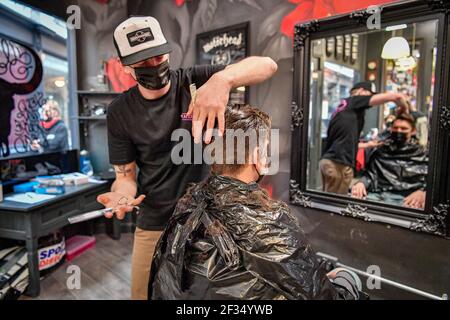 Barber Olly D'Urso schneidet David Saunders, 38, aus Cardiff, bei Sleep When You're Dead Barbers in Duke St Arcade, Cardiff, da David seinen ersten Haarschnitt seit Sommer 2020 hat. Friseure und Barbiere in Wales werden ab Montag zum ersten Mal im Jahr 2021 wiedereröffnet, da die Beschränkungen für Coronaviren gelockert werden, was die erste Aufhebung der Regeln für Dienstleistungen mit engen Kontakten seit der Sperre von Wales am 20. Dezember markiert. Geschäfte wie Nagelstudios und Schönheitssalons werden voraussichtlich bis mindestens April 12 geschlossen bleiben. Bilddatum: Montag, 15. März 2021. Stockfoto