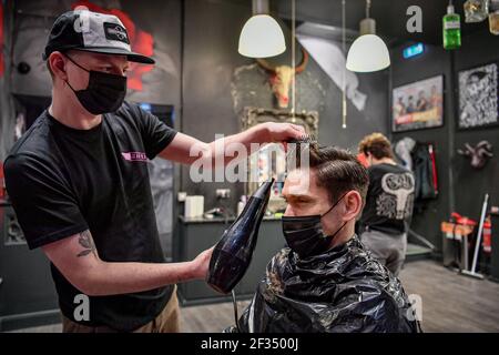 Barber Olly D'Urso stylen die Haare von David Saunders, 38, aus Cardiff, bei Sleep When You're Dead Barbers in Duke St Arcade, Cardiff, da David seinen ersten Haarschnitt seit Sommer 2020 hat. Friseure und Barbiere in Wales werden ab Montag zum ersten Mal im Jahr 2021 wiedereröffnet, da die Beschränkungen für Coronaviren gelockert werden, was die erste Aufhebung der Regeln für Dienstleistungen mit engen Kontakten seit der Sperre von Wales am 20. Dezember markiert. Geschäfte wie Nagelstudios und Schönheitssalons werden voraussichtlich bis mindestens April 12 geschlossen bleiben. Bilddatum: Montag, 15. März 2021. Stockfoto