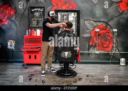 Barber Olly D'Urso schneidet David Saunders, 38, aus Cardiff, bei Sleep When You're Dead Barbers in Duke St Arcade, Cardiff, da David seinen ersten Haarschnitt seit Sommer 2020 hat. Friseure und Barbiere in Wales werden ab Montag zum ersten Mal im Jahr 2021 wiedereröffnet, da die Beschränkungen für Coronaviren gelockert werden, was die erste Aufhebung der Regeln für Dienstleistungen mit engen Kontakten seit der Sperre von Wales am 20. Dezember markiert. Geschäfte wie Nagelstudios und Schönheitssalons werden voraussichtlich bis mindestens April 12 geschlossen bleiben. Bilddatum: Montag, 15. März 2021. Stockfoto