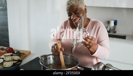 Glückliche schwarze Seniorin kocht gesundes Essen in der Küche Stockfoto