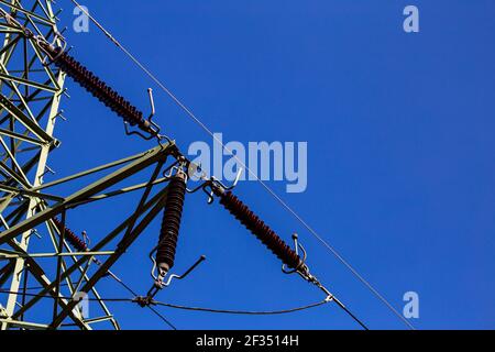 Nahaufnahme von Isolatoren auf Hochspannungsmasten vor dem Hintergrund des blauen Himmels. Hergestellt an einem sonnigen Tag, tiefblauer Himmel Stockfoto