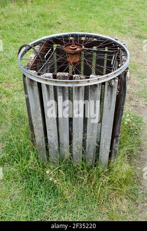 Einfache Idee, ein altes Rad zu recyceln, um ein zu schützen Mülltonne im Park Stockfoto