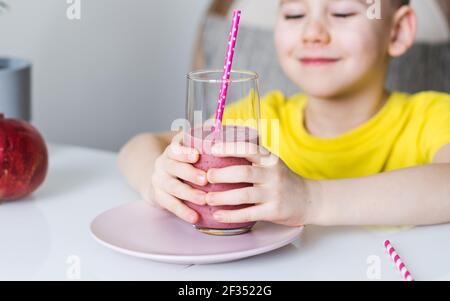 Ein süßer Junge hält ein Glas Beerenmoothies in den Händen. Das Konzept der gesunden Ernährung. Speicherplatz kopieren. Stockfoto