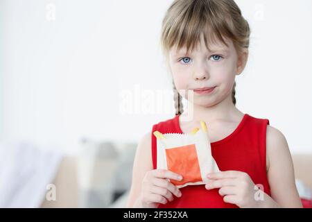 Das kleine Mädchen hält pommes in der Packung in den Händen Stockfoto