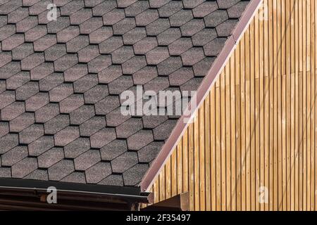 Modernes Gebäudeelement mit gefliestem dunklen Dach und Holzwandhintergrund. Stockfoto