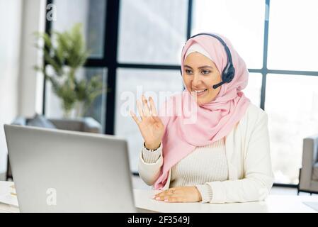 Muslimische Geschäftsfrau, Schülerin, Lehrerin, Tutorin im Headset für Videokonferenzen, Telefonieren am Laptop oder Computer, Sprechen mit Webcam, Lernen oder Lehren im Online-Chat, Fernseminar aus der Ferne, Lehrkonzept Stockfoto