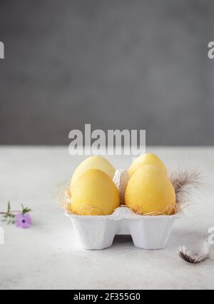 Gelbe ostereier gefärbt mit natürlichen Farbstoff - Kurkuma Gewürze. Frohe Ostern. Vorbereitung auf den Urlaub. Vertikales Bild. Grauer Hintergrund. Kopierbereich Stockfoto
