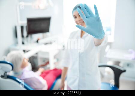 Ärztin versteckt sich hinter ihrer Handfläche vor der Kamera Stockfoto