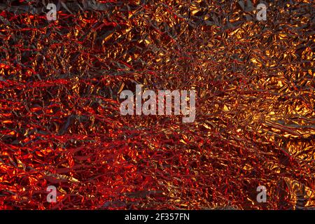Abstrakt golden rot Aluminium zerknittert Folie Hintergrund Textur reflektierend rot Und goldenes Licht Stockfoto