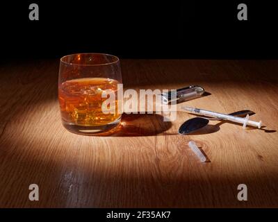 Whiskey mit Eis in einem Glas, Pillen und Drogen sind in der Nähe, das Konzept der Schaden von Alkohol und Drogen auf den menschlichen Körper Stockfoto