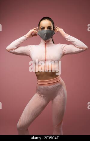 Charmante junge Frau in Sportswear setzen auf Gesichtsmaske Stockfoto