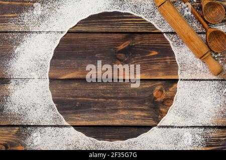 Mehl verstreut in Form eines Kreises, Nudelholz und weiße Leinenserviette auf einem alten Holzhintergrund. Für Text platzieren. Background zum Backen. Stockfoto