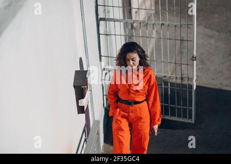 Junge Gefangene Frau in orange Klage im Gefängnis Rauchen. Weiblich in bunten Overalls Porträt Stockfoto