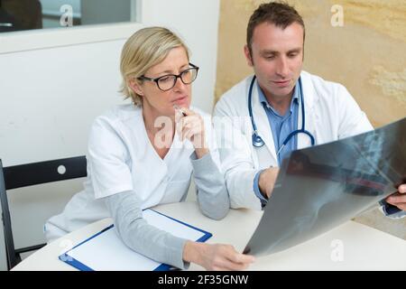 Ärzte, die eine Röntgenaufnahme eines Patienten untersuchen Stockfoto
