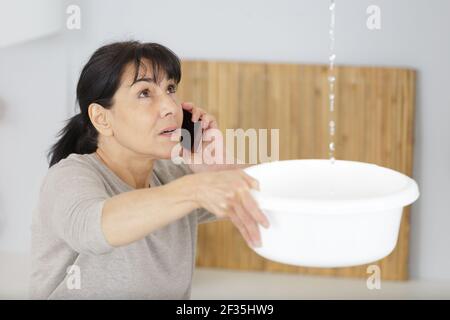 Traurige reife Frau ruft Klempner vor Wasser Leck Stockfoto