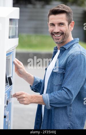 Ein Mann, der für den Parkplatz am Automaten bezahlt Stockfoto