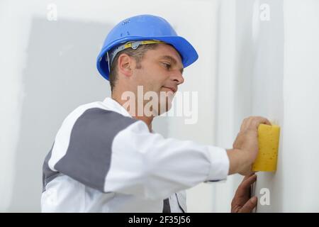 Arbeiter mit Sicherheitsgurt wäscht die Wand Stockfoto