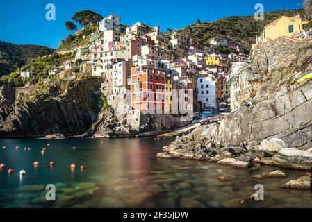 Panoramablick auf farbige Häuser auf steilen Felsklippen über dem Meer am Hafen von Riomaggiore, Cinque Terre, Ligurien, Italien. Stockfoto