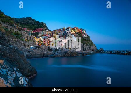 Panoramablick auf die kleine Stadt der Klippe nach Sonnenuntergang. Foto von bunten Häusern im Nationalpark Cinque Terre, Ligurien, Italien. Stockfoto