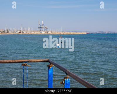 Blick vom Pier über den Mann, der im Kanu paddelt und im mittelmeer schwimmende Menschen in Larnaca, Zypern. Stockfoto