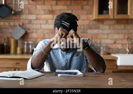 Gestresster schwarzer Mann sitzen von Copybooks Smartphone von Informationen überlastet Stockfoto