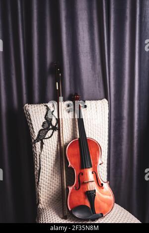 Musik und Violine im Theater. Venezianische Maske mit alter Geige Komposition. Maskerade - Phantom der Oper Maske mit Geige, Geige und Bogenstandin Stockfoto