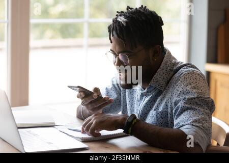 Enthusiastische junge afrikanische männliche Freiberufler machen gute Fortschritte in Multitasking Stockfoto