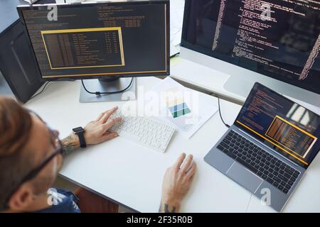High-Angle-Ansicht bei männlichen Programmierer schreiben Code, während mit mehreren Computern in IT-Entwickler Büro, kopieren Raum Stockfoto