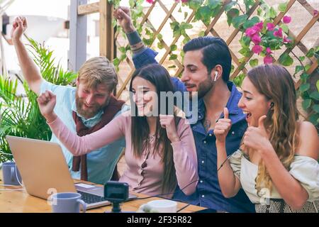 Glückliche Freunde oder Fußballfans, die Fußball auf dem Laptop schauen und den Sieg im Barsport feiern. Freundschafts-, Sport- und Unterhaltungskonzept. Stockfoto