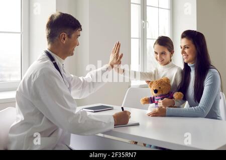 Freundlicher Kinderarzt gibt fünf an seine kleine Patientin in der Arztpraxis. Stockfoto