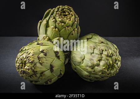 Eine selektive Fokusaufnahme von Artischocken auf einer Tafel auf Schwarzer Hintergrund Stockfoto