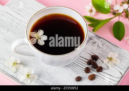 Tasse starken Espresso Kaffee und zarten Frühlingsblumen auf rosa Hintergrund. Frühling und Good Morning Konzept. Stockfoto