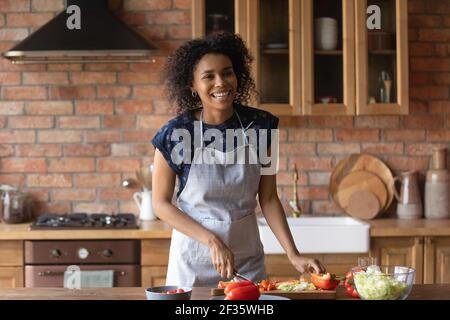 Fröhliche junge afro amerikanische Dame schneiden Gemüsesalat zum Mittagessen Stockfoto