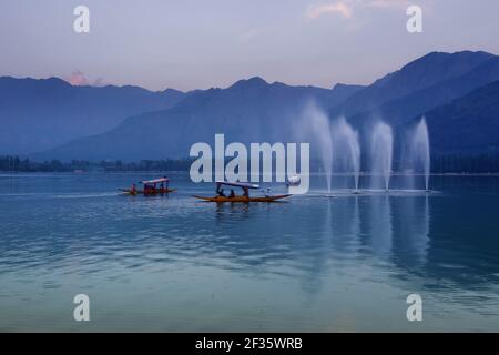 Spiegelung der Himalaya-Berge am Dal Lake, Srinagar, Jammu und Kaschmir, Indien. Hausboote schwimmen in der Nähe von Brunnen auf dem See am späten Nachmittag. Stockfoto