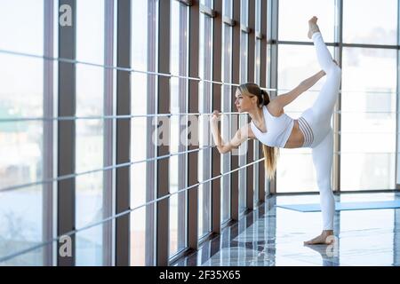 Fitness Mädchen üben Garn. Flexible Frau im Turnsaal erstreckt sich durch das Panoramafenster Stockfoto