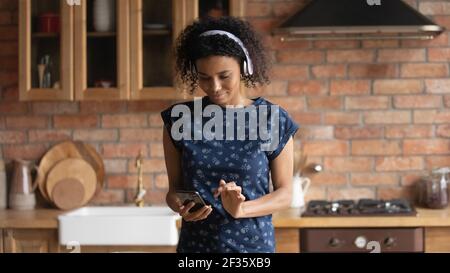 Schwarze Hausfrau tragen Kopfhörer auf der Suche nach Rezept online mit Telefon Stockfoto
