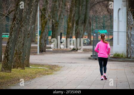 Blonde Mädchen laufen oder joggen allein mit Kopfhörer oder Headset Im Park in der Stadt Stockfoto