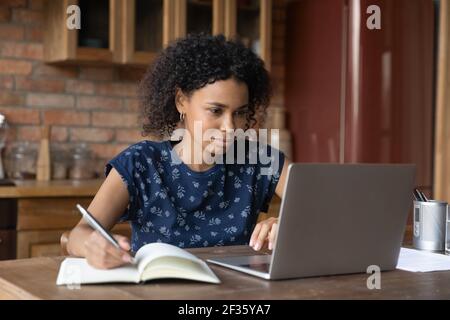 Afrikanische weibliche Studie mit Laptop nehmen Sie sich Notizen von Internet-Vortrag Stockfoto