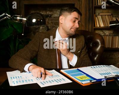 Ein kranker, müder Mann löst seine Krawatte spät bei der Arbeit. Stockfoto