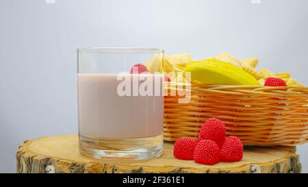 Fruchtjoghurt im Glas auf einem Holzbrett und mit Früchten in einem Korb. Stockfoto
