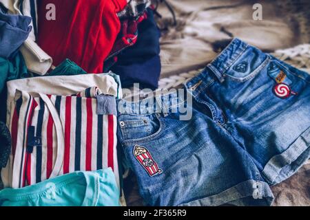 Wahl Kleidung Konzept mit chaotischen Haufen auf Hintergrund und Jeans Shorts vorne Stockfoto