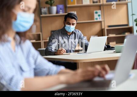 Indischer Business Mann trägt Gesichtsmaske arbeiten auf Laptop im Büro Coworking. Stockfoto