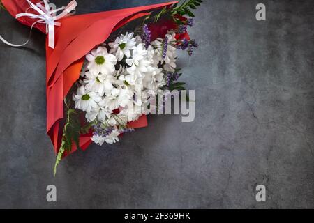 Ein wunderschön gestalteter Strauß aus weißen Chrysanthemen und roten Rosen auf dunklem Hintergrund. Draufsicht, Kopierbereich Stockfoto