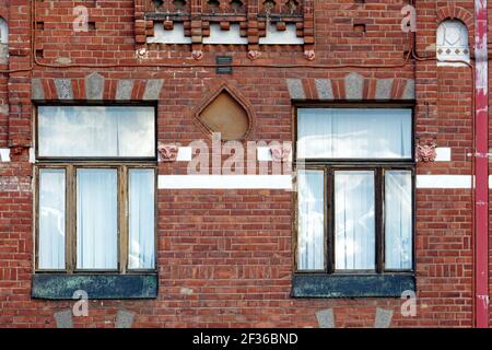 Zwei rechteckige Fenster mit alten Holzrahmen auf dem Hintergrund einer alten roten Ziegelwand mit Fliesen. Aus den Fenstern der Welt-Serie. Stockfoto