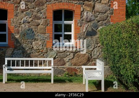 Zwei weiße Bänke stehen im Hof eines alten Steinhaus an einem hellen sonnigen Tag Stockfoto