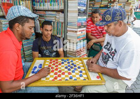 Santo Domingo Dominikanische Republik, Calle Caracas Outdoor-Markt, Buchhandlung für gebrauchte Bücher Hispanic Schwarze Männer spielen Dame, Stockfoto